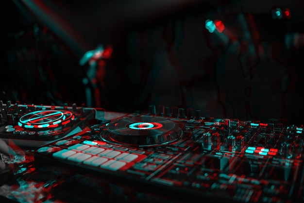 DJ-Konsole zum Mischen von Musik mit verschwommenen Leuten, die auf einer Nachtclubparty tanzen. Schwarzweiß mit 3D-Glitch-Virtual-Reality-Effekt