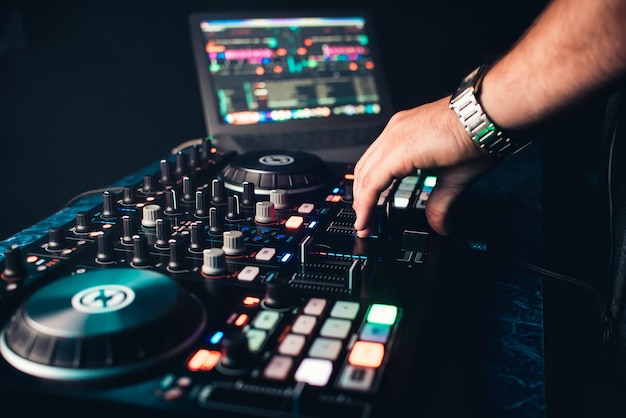 DJ mezcla y gestiona música en un tablero profesional de música contemporánea