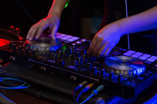 DJ mezclando pistas en un mezclador en un club nocturno.