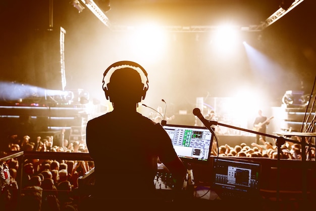 DJ con multitud de personas en una fiesta de discoteca bajo la luz del escenario