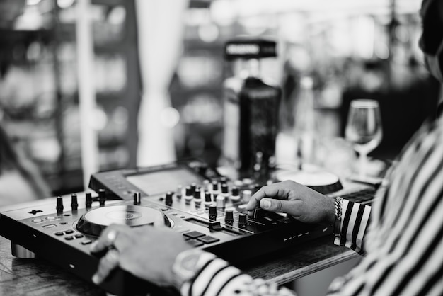 Dj negro tocando música en el bar de cócteles al aire libre - Concepto de entretenimiento y fiesta - Enfoque en la mano derecha