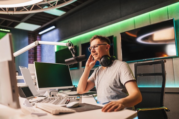 El DJ presenta el programa y se comunica con la audiencia al aire en la estación de radio. El locutor lee las noticias. Un locutor de radio habla por un micrófono y graba un podcast.