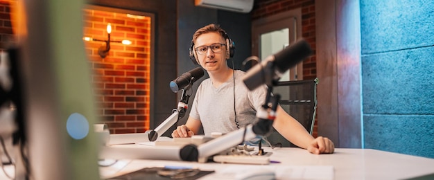 El DJ presenta el programa y se comunica con la audiencia al aire en la estación de radio. El locutor lee las noticias. Un locutor de radio habla por un micrófono y graba un podcast.