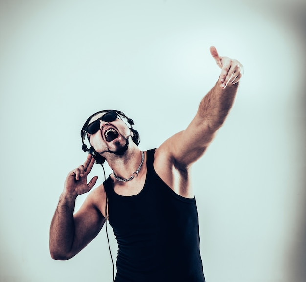 DJ - Rapper in Kopfhörern nimmt den Rap- und Breakdance-Tanz auf einem hellen Hintergrund auf. Das Foto hat einen leeren Platz für Ihren Text