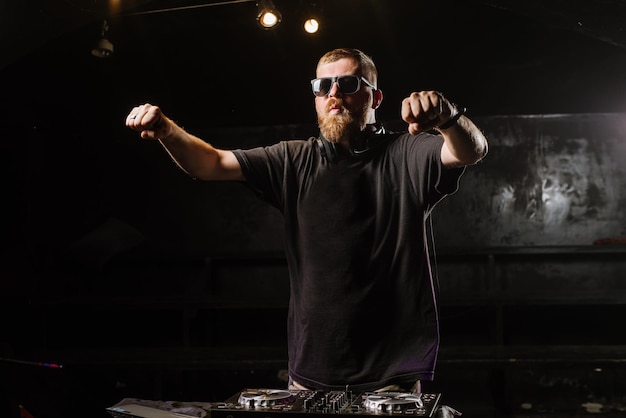 DJ spielt auf einem Mixer im Club auf schwarzem Hintergrund