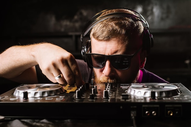 DJ toca em um mixer no clube em fundo preto