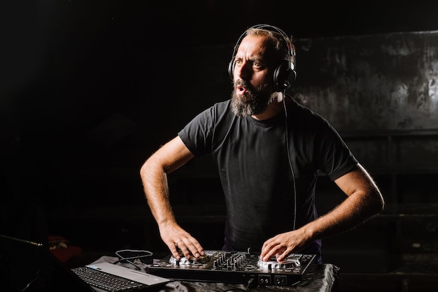 DJ toca en un mezclador en el club sobre fondo negro