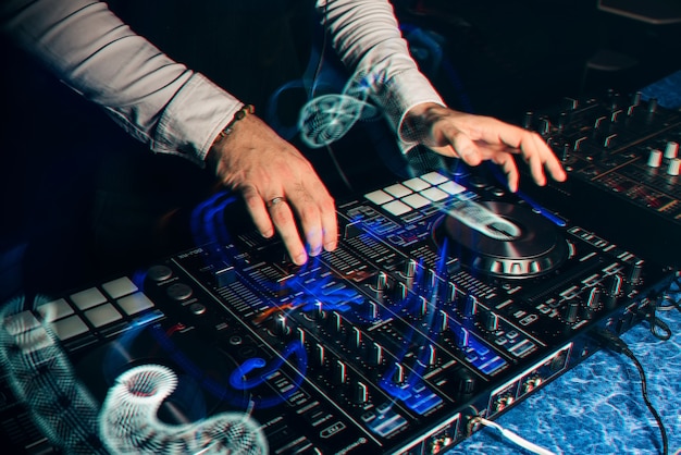 DJ toca en el mezclador de música en una discoteca