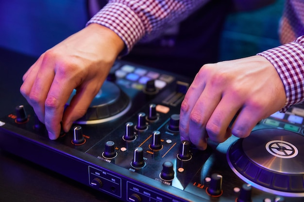 Dj tocando música con tocadiscos y mezclador de sonido en el escenario de la discoteca