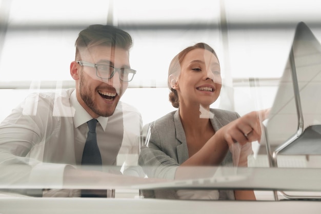 Do casal de negócios sorridentes sentados na mesa o conceito de trabalho em equipe