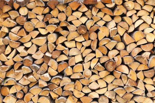 Doblados en una fila de troncos cortados en pedazos para quemarlos en el horno, primer plano cerca de una casa en el pueblo