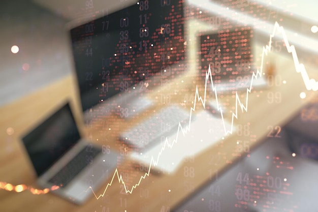 Doble exposición de un diagrama financiero creativo abstracto con un mapa mundial y un escritorio moderno con una computadora en el fondo del concepto bancario y contable