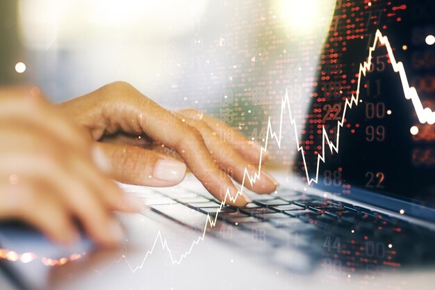 Doble exposición de diagrama financiero creativo abstracto con mapa mundial y con las manos escribiendo en el teclado de la computadora en concepto de contabilidad y banca de fondo