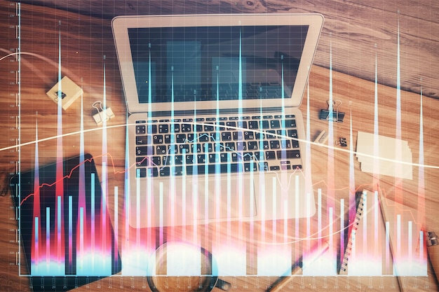 Doble exposición del dibujo del gráfico financiero sobre el fondo de la tabla con computadora Concepto de investigación y análisis Vista superior