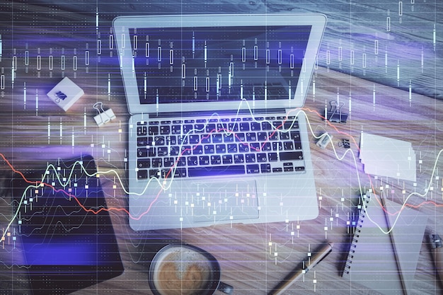 Doble exposición del dibujo del gráfico financiero sobre el fondo de la tabla con computadora Concepto de investigación y análisis Vista superior