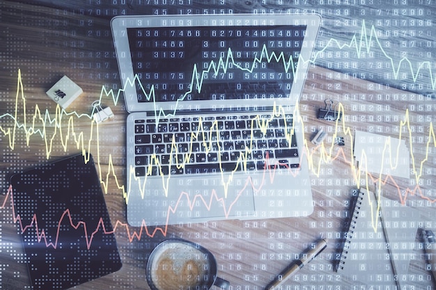 Doble exposición del dibujo del gráfico financiero sobre el fondo de la tabla con computadora Concepto de investigación y análisis Vista superior