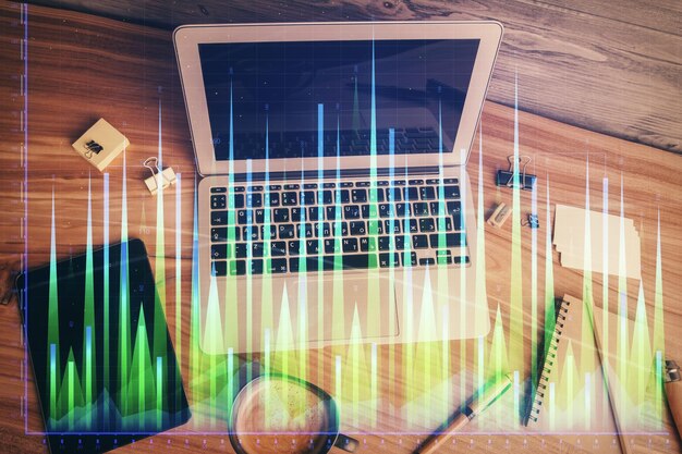 Doble exposición del dibujo del gráfico financiero sobre el fondo de la tabla con computadora Concepto de investigación y análisis Vista superior