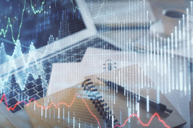 Doble exposición del dibujo de gráficos financieros y el escritorio con café y artículos en el fondo de la mesa Concepto de negociación en el mercado de divisas
