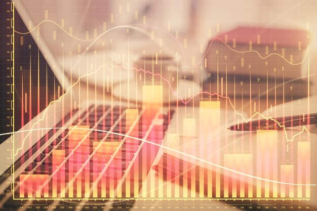 Doble exposición del dibujo de gráficos financieros y el escritorio con café y elementos en el fondo de la mesa Concepto de comercio en el mercado de divisas