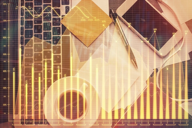 Doble exposición del gráfico financiero sobre el fondo de la mesa con computadora Concepto de investigación y análisis Vista superior