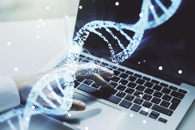 Doble exposición del holograma de ADN creativo y manos escribiendo en una computadora portátil en el concepto de investigación de ADN y bioingeniería de fondo