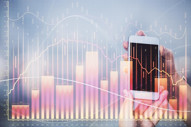 Doble exposición de holograma de boceto de gráfico de divisas y mujer sosteniendo y usando un dispositivo móvil Concepto de mercado de valores