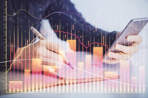 Doble exposición del holograma de boceto gráfico de forex y mujer sosteniendo y usando un concepto de mercado de valores de dispositivo móvil