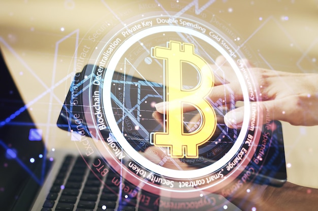 Doble exposición del holograma creativo del símbolo de Bitcoin y el trabajo manual con una tableta digital en segundo plano Concepto de minería y cadena de bloques