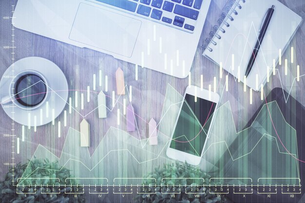 Doble exposición del holograma del gráfico financiero sobre el escritorio con el teléfono Vista superior Concepto de plataforma de comercio móvil