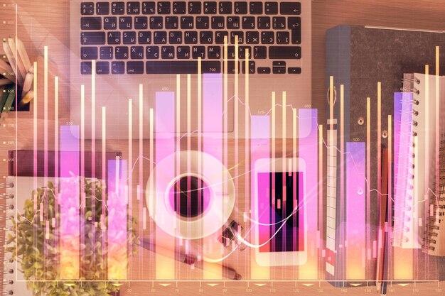 Doble exposición del holograma del gráfico financiero sobre el escritorio con el teléfono Vista superior Concepto de plataforma de comercio móvil