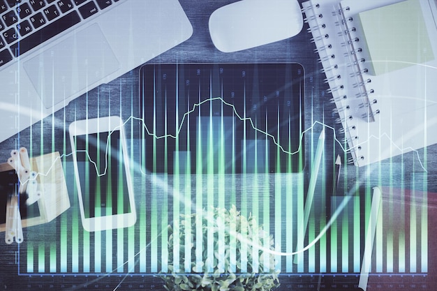 Doble exposición del holograma del gráfico Forex sobre el escritorio con el teléfono Vista superior Concepto de plataforma de comercio móvil