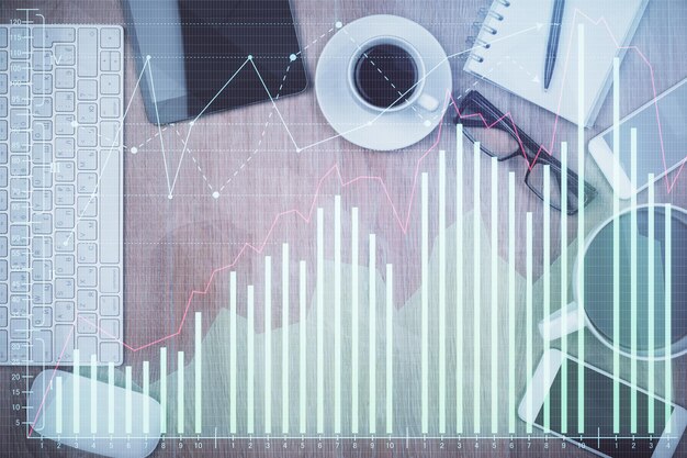 Doble exposición del holograma de gráficos financieros en el escritorio con el teléfono Vista superior Concepto de plataforma de comercio móvil