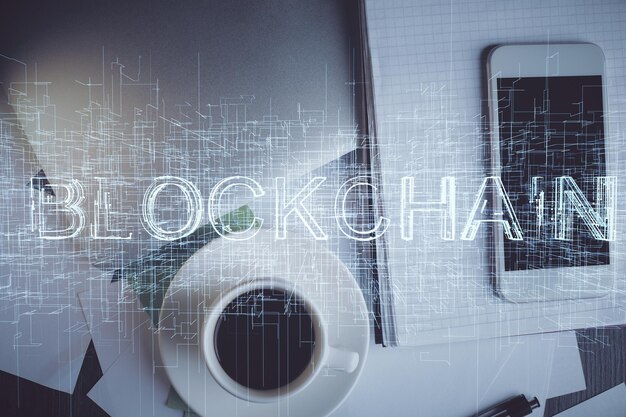 Doble exposición del holograma del tema blockchain sobre la mesa con el teléfono Vista superior Concepto de tecnología criptográfica