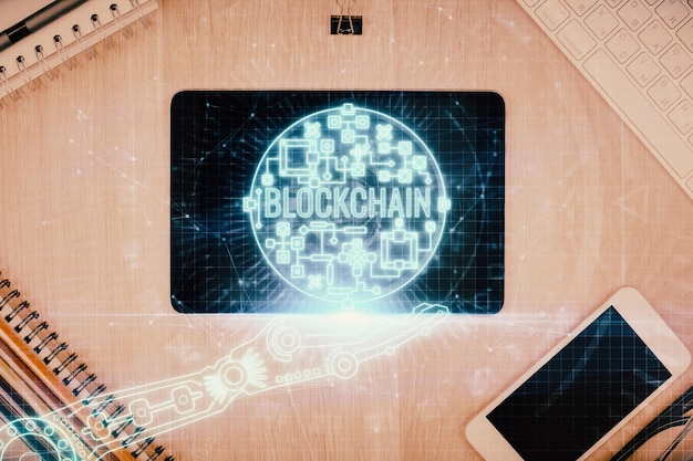 Doble exposición del holograma del tema blockchain sobre la mesa con el teléfono Vista superior Concepto de tecnología criptográfica