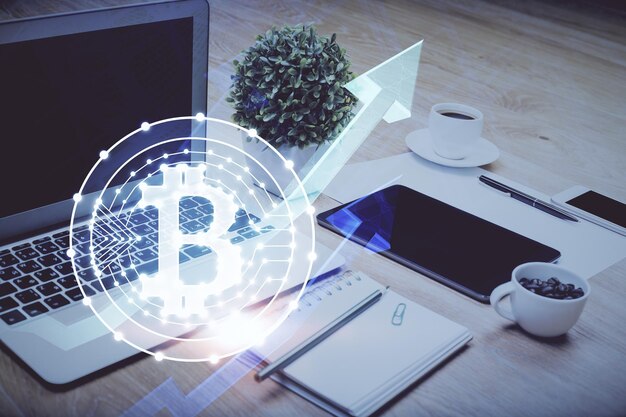 Doble exposición del holograma temático blockchain y criptoeconomía y mesa con fondo de computadora Concepto de criptomoneda bitcoin
