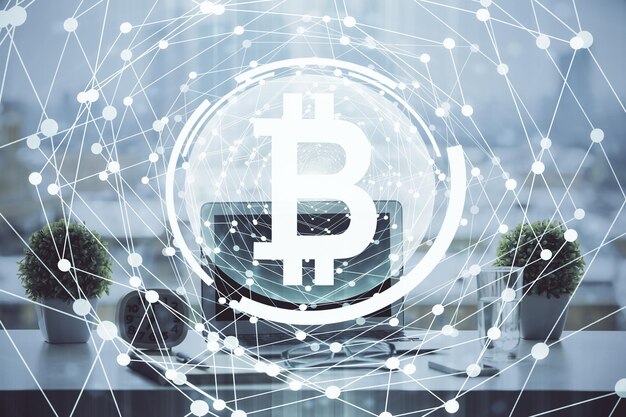 Doble exposición del holograma temático blockchain y criptoeconomía y mesa con fondo de computadora Concepto de criptomoneda bitcoin