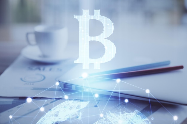 Doble exposición del holograma temático blockchain y criptoeconomía y mesa con fondo de computadora Concepto de criptomoneda bitcoin