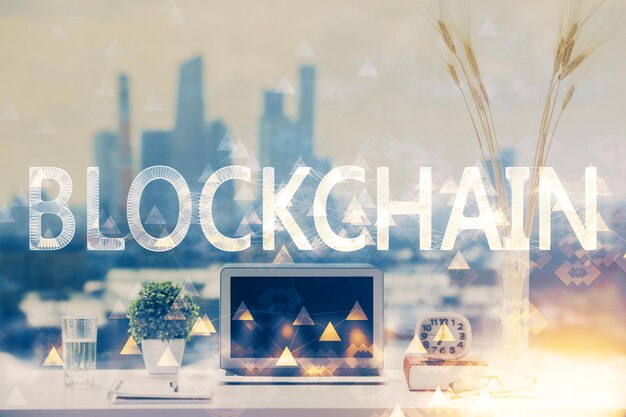 Doble exposición del holograma temático blockchain y criptoeconomía y mesa con fondo de computadora Concepto de criptomoneda bitcoin