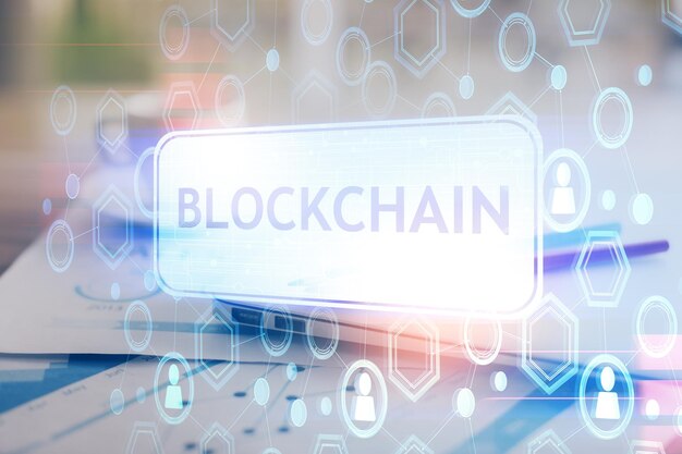 Doble exposición del holograma temático blockchain y criptoeconomía y mesa con fondo de computadora Concepto de criptomoneda bitcoin
