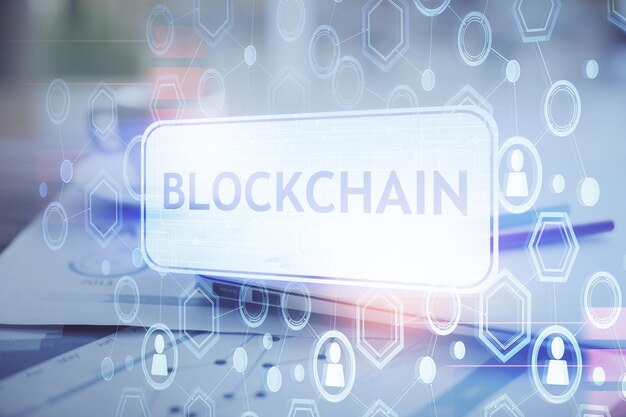 Doble exposición del holograma temático blockchain y criptoeconomía y mesa con fondo de computadora Concepto de criptomoneda bitcoin