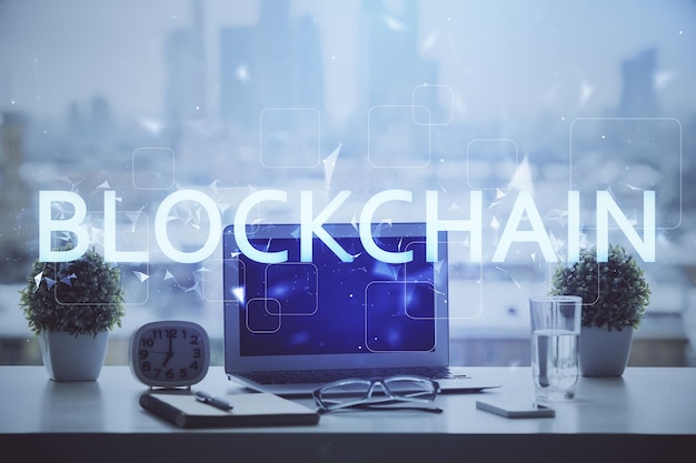 Doble exposición del holograma temático blockchain y criptoeconomía y mesa con fondo de computadora Concepto de criptomoneda bitcoin