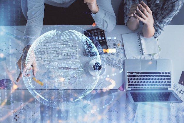 Doble exposición de un hombre y una mujer trabajando juntos y un holograma de mapa mundial dibujando el concepto de red internacional Fondo de computadora Vista superior