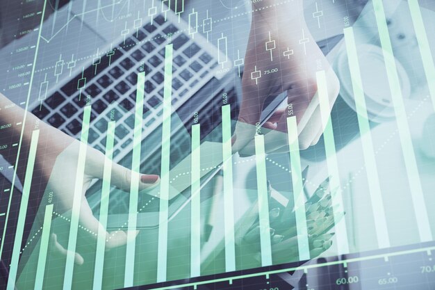 Doble exposición de manos de empresaria escribiendo en computadora y gráfico financiero holograma dibujo concepto de análisis del mercado de valores