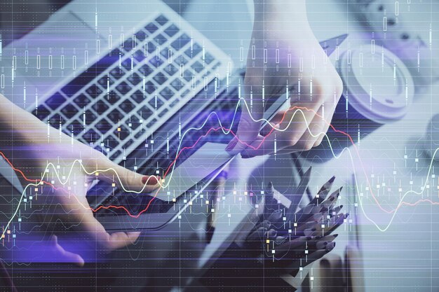 Doble exposición de manos de empresaria escribiendo en computadora y gráfico financiero holograma dibujo concepto de análisis del mercado de valores