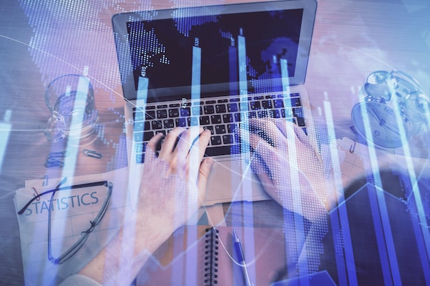 Doble exposición de las manos del hombre escribiendo sobre el teclado de la computadora portátil y el dibujo del holograma del gráfico forex Vista superior Concepto de mercados financieros