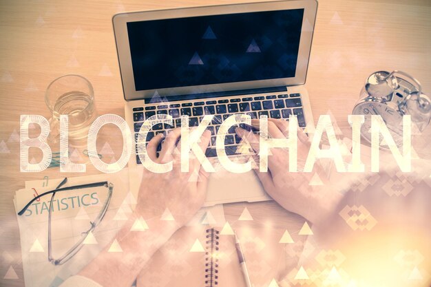 Doble exposición de las manos del hombre escribiendo sobre el teclado de la computadora y el tema de la criptomoneda dibujo holográfico vista superior concepto de Blockchain