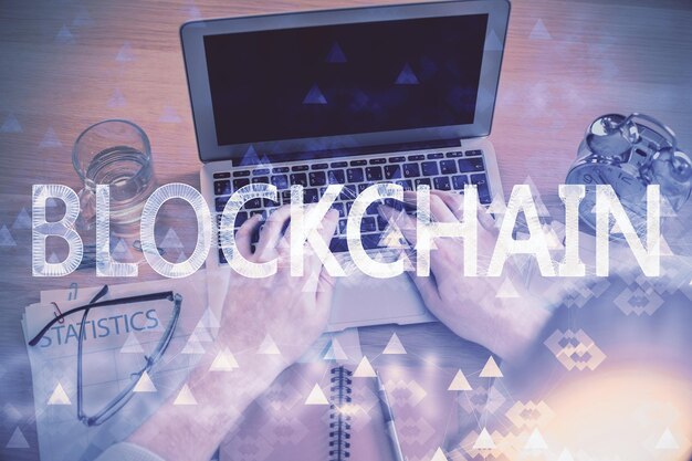 Doble exposición de las manos del hombre escribiendo sobre el teclado de la computadora y el tema de la criptomoneda dibujo holográfico vista superior concepto de Blockchain