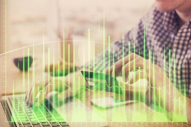 Doble exposición de manos de hombre sosteniendo una tarjeta de crédito y dibujo de gráficos de Forex Comercio de acciones y fintech digital en el concepto de comercio electrónico en Internet