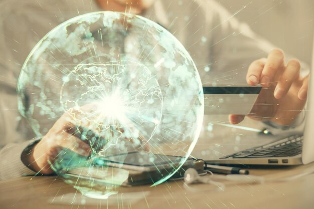Doble exposición de manos de hombre sosteniendo una tarjeta de crédito y un tema de negocios en Internet dibujando el concepto de fintech digital y comercio electrónico