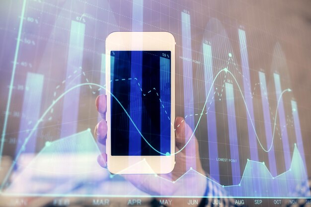 Foto doble exposición de las manos del hombre sosteniendo y usando un dispositivo digital y dibujo de gráficos de divisas concepto de mercado financiero